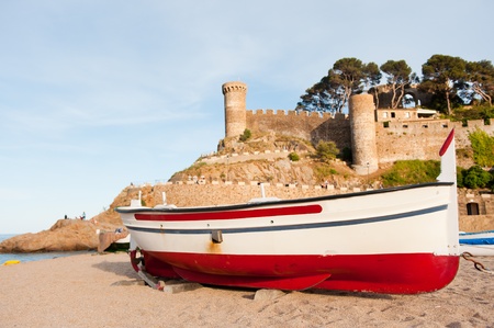 Fishing boat in front of the castle in Tossa de Mar at the Spanish coastの写真素材