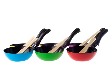 Many colorful frying panswith spatulas isolated over whiteの写真素材