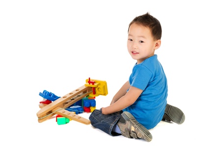 Little Chinese boy with light handicap playing with wooden crane an blocs の写真素材