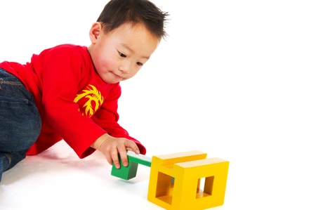 Portrait of a Chinese boy playing with wooden puzzle isolated over whiteの写真素材