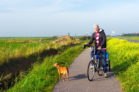 Man with his dog at the bike in Dutch landscapeの写真素材