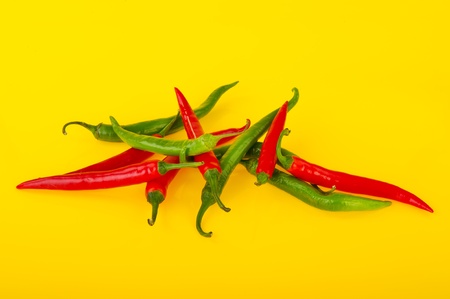 Fresh red and green chili peppers on yellow backgroundの写真素材