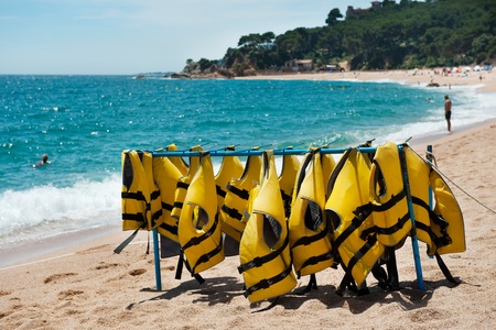 Yellow diving jackets on a rack at the beachの写真素材