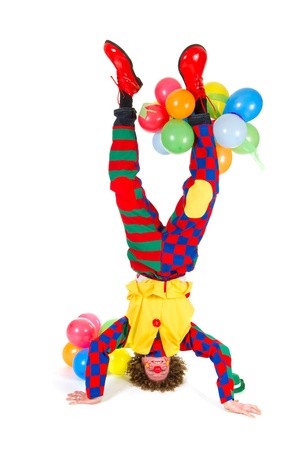 Funny clown with balloons in headstand on white backgroundの写真素材