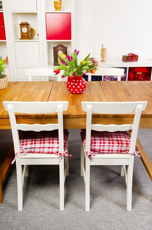 Table and chairs in interior with vase of colorful tulipsの写真素材