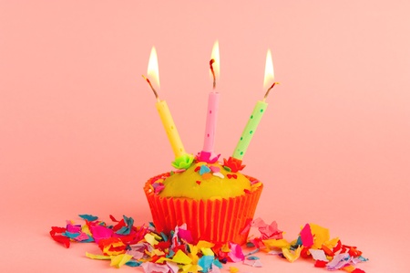 Birthday cupcake with burning candles on pinkの写真素材