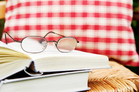 Still life with books and reading glasses on a chairの写真素材