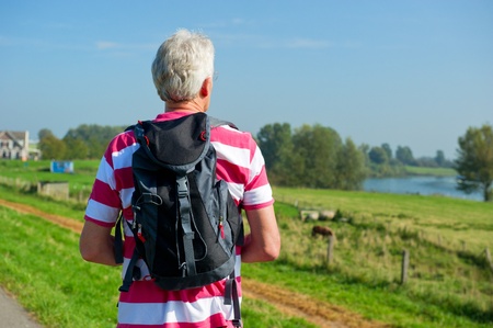Elderly man is hiking with backpack in natureの写真素材