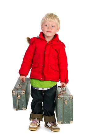 Little boy with suitcases and coat is walking away from homeの写真素材