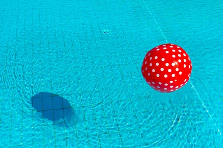 Floating red beach ball in swimming poolの写真素材