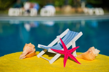 Beach chair and shells with star near swimming poolの写真素材