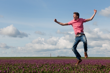 Young man is jumping above the typical dutch tulipsの写真素材