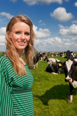 Young blond Dutch girl in farm field with black and white cowsの写真素材