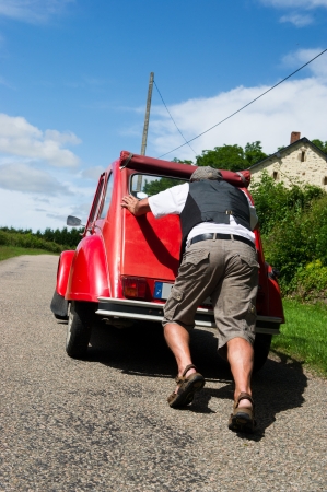 Typical French man is pushing his car after a breakdownの写真素材