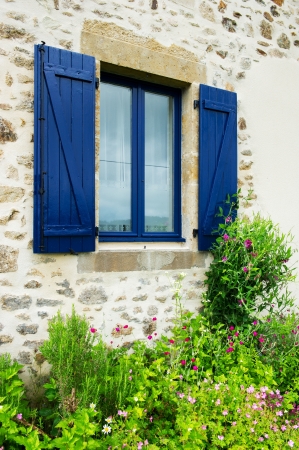 French window with blue shutters and flower garden outdoorの写真素材