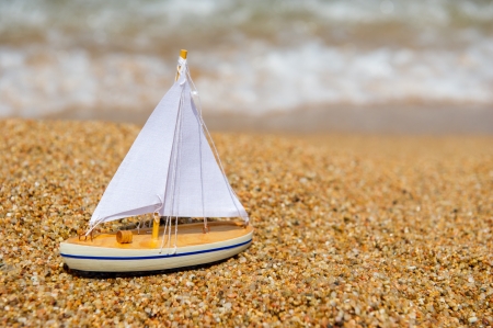 Wooden toy sail boat at the beach
