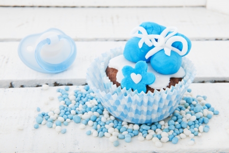 Blue cupcake with baby shoes and comforterの写真素材