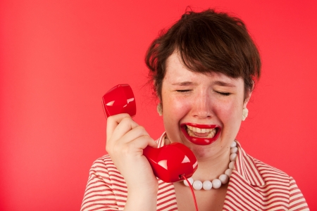 Young woman on red is crying on the telephoneの写真素材