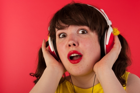 Young girl is listening music with headphones on redの写真素材