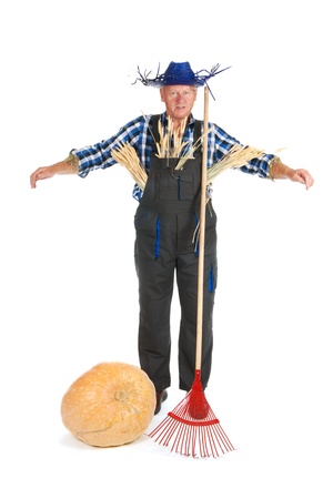 Human scarecrow with pumpkin and gardening equipmentの写真素材