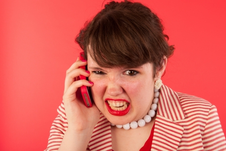 Young woman is having an angry phone call at the smartphoneの写真素材