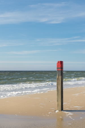 Wooden red beach pole at the coast of the Northseaの写真素材