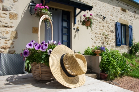 French house with flowers in the garden and straw hatの写真素材