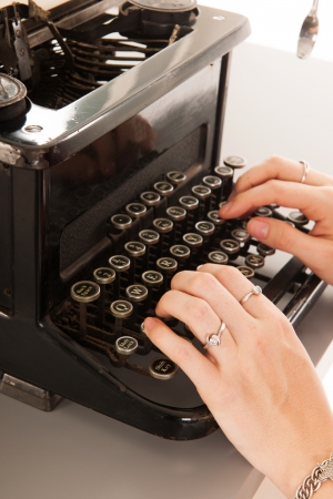 Woman is typing on black vintage typewriterの写真素材