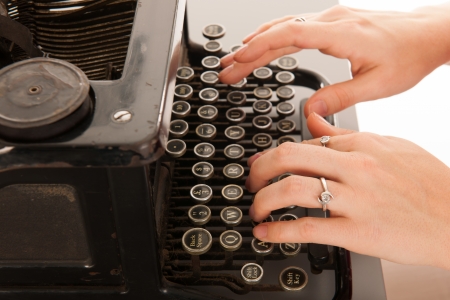Woman is typing on black vintage typewriterの写真素材