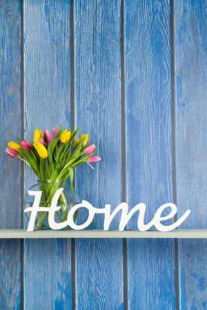 Home in white letters with colorful bouquet tulips in pink and yellow isolated on backgroundの写真素材