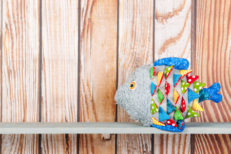 Stuffed colorful funny fantasy fish at home on wooden backgroundの写真素材