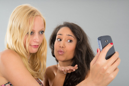 Girlfriends taking selfie with cell phone while kissingの写真素材