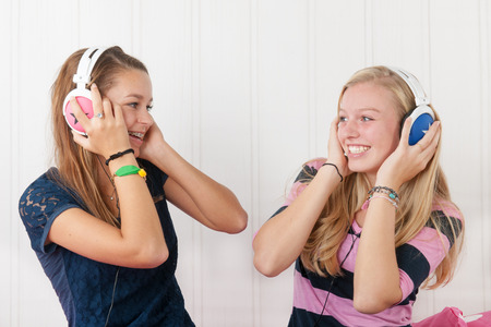Two teenager girls listening to music with headphonesの写真素材