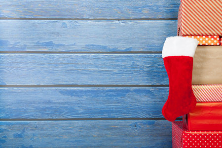 Red presents on white floor with blue wooden wall with stocking for Christmas