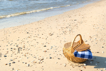 Picnic basket with blue checked cloth at the beachの写真素材