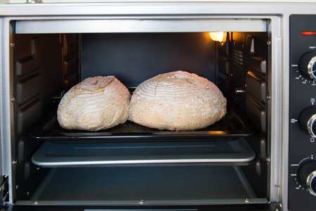 Baking rustic brown bread in oven at homeの写真素材