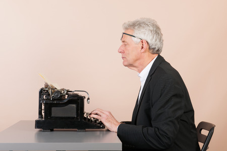 Senior man at the office working with old black typewriter