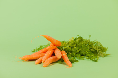 Bunch fresh carrots on green backgroundの写真素材