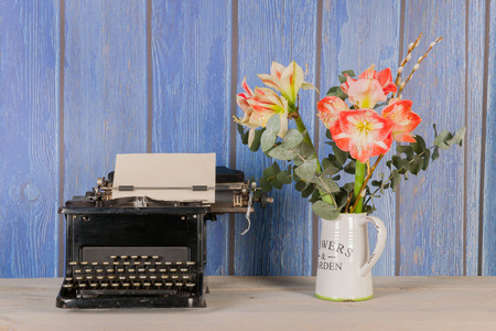 Antique black typewriter in interior with vase flowersの写真素材