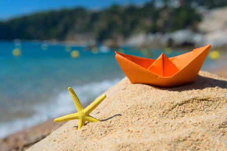 Paper boat and starfish in the sand at the beachの写真素材