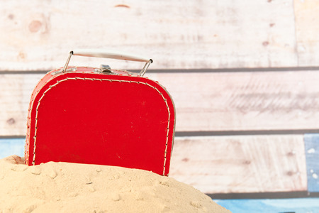 Vintage red suitcase in sand at the beachの写真素材