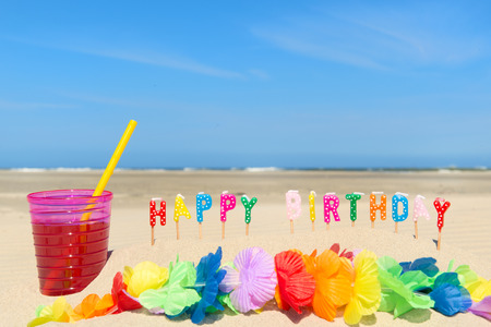 glass lemonade with drinking straw and happy birthday candles at the beachの写真素材