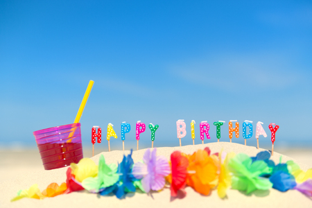 Happy birthday candles and flower garland at the beachの写真素材