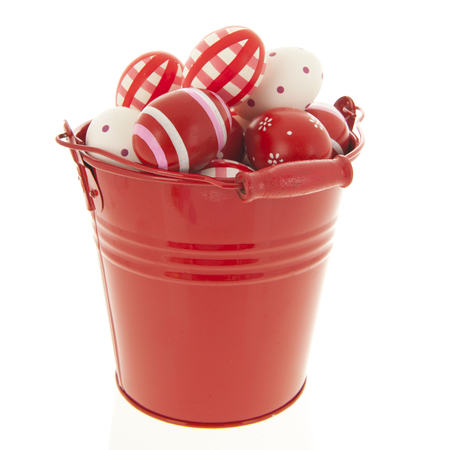 Red bucket full with easter eggs isolated over white backgroundの写真素材