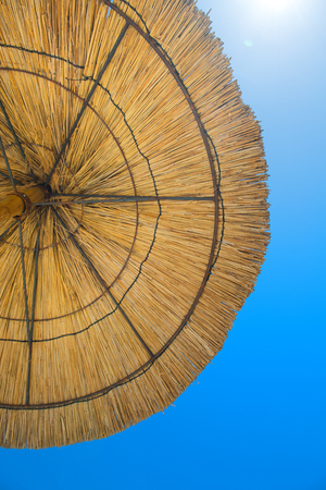 straw parasol against blue skyの写真素材