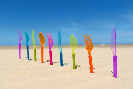Colorful silverware standing in sand at the beach