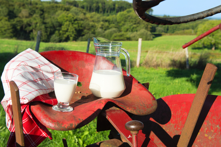 Decanter and glass with milk on the tractor at the farmの写真素材