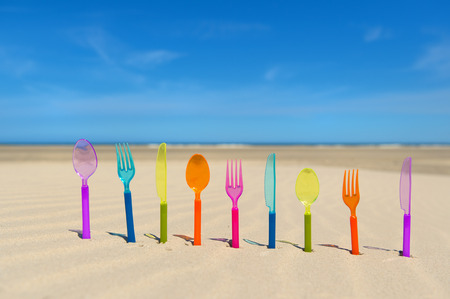 Colorful silverware standing in sand at the beach