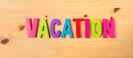 Word vacation in colorful letters on wood