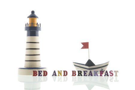 Bed and breakfast at the coast with lighthouse and paper boatの写真素材